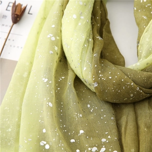 Detailed close-up of green gradient scarf with silver foil accents and soft fabric texture