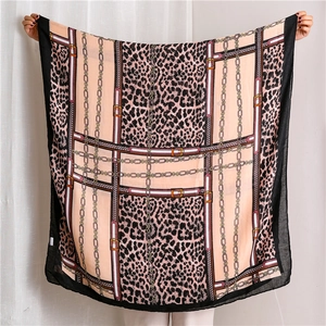 Detailed close-up of leopard print and gold chain patterns on a soft cotton linen scarf