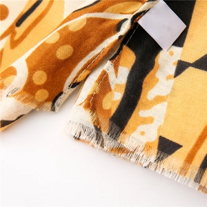 Détail macro d'une écharpe jaune en coton et lin à motifs géométriques avec bords à franges