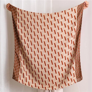 Detail of a large silk scarf with orange and brown geometric V patterns held by hands