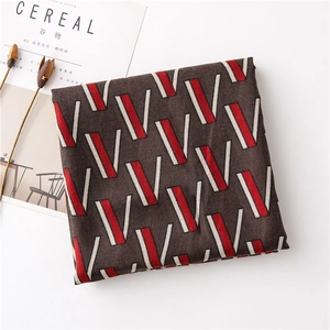Detail of soft folded scarf featuring geometric V-pattern over brown fabric background