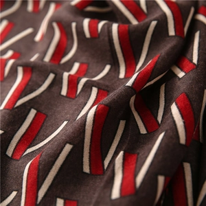 Macro shot of silk scarf fabric showing red geometric patterns and soft drapery texture