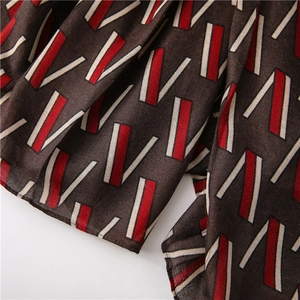 Detail of dark brown scarf fabric with red and beige geometric V-pattern weave