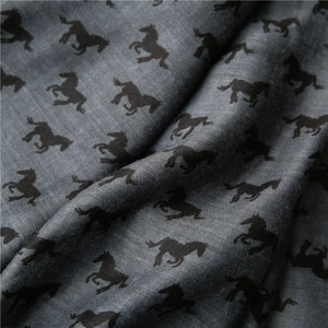 Macro view of dark grey cotton scarf fabric featuring dense black galloping horse patterns