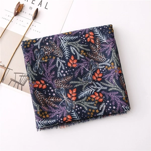 Dettaglio della sciarpa in cotone lino blu scuro con stampe floreali, libellule e frange