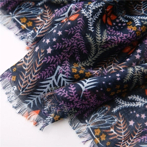 Dettaglio della sciarpa in cotone e lino blu navy con motivi floreali e bordi a frange