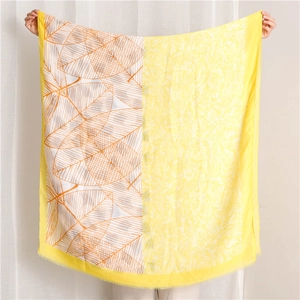 Detailed close-up of yellow and white scarf with leaf patterns and fringe edge