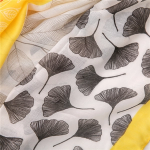 Detail of ginkgo leaf print scarf with yellow hem and soft fabric texture