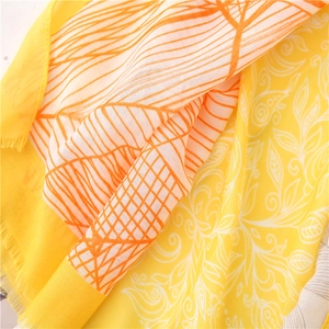 Detailed texture of cotton scarf with vibrant leaf prints and frayed tassel edges