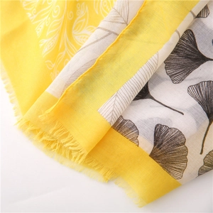 Close-up of yellow floral and black ginkgo leaf patterns on cotton linen scarf with fringe