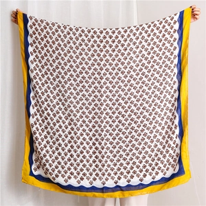 Detail of floral linen scarf featuring red flower patterns and navy wavy border trim