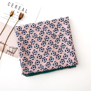 Detail of pink cotton linen scarf with blue floral prints and dark green hem