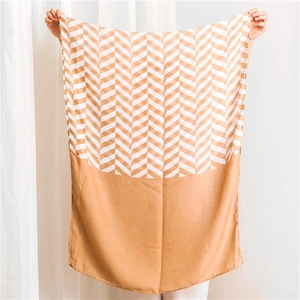 Detail view of earth-tone herringbone pattern and solid color block oversized shawl