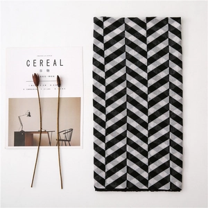 Detailed view of rectangle scarf with black and gray diagonal plaid pattern on a magazine