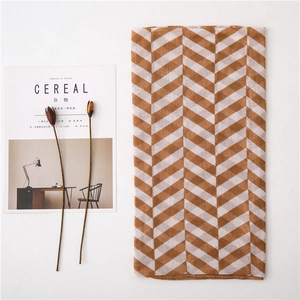 Detail of soft caramel and beige herringbone pattern scarf with elegant fringe texture