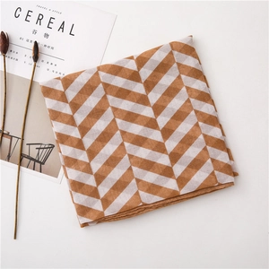 Detailed flat lay of brown herringbone patterned scarf with elegant fringe and minimalist decor