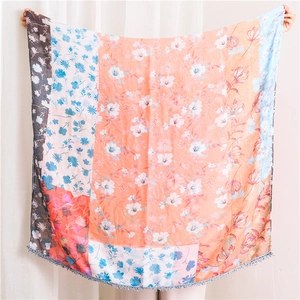 Detail of floral patchwork pattern and delicate pompom fringe on a light scarf
