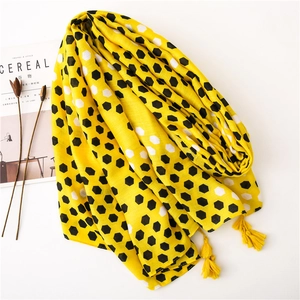 Yellow linen scarf with black hexagonal honeycomb print and tassels on white background