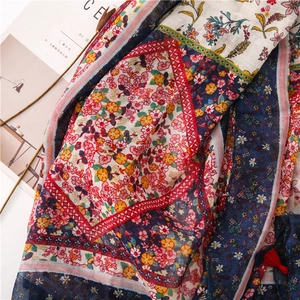 Detail of bohemian scarf with floral patterns, geometric borders and red tassels