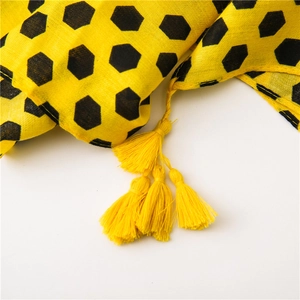 Detailed macro view of yellow cotton linen scarf with black honeycomb print and tassels