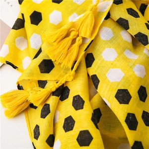 Detail shot of yellow honeycomb pattern scarf featuring cotton linen fabric and soft tassels