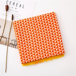 Detail eines geometrischen Schals mit orangefarbenem Muster und gelben Fransen