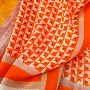 Nahaufnahme des leichten Baumwollschals mit orange-schwarzem geometrischem Rautenmuster