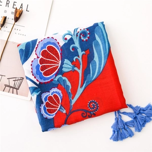 Detailed view of red and blue floral cotton linen scarf with elegant fringe trim