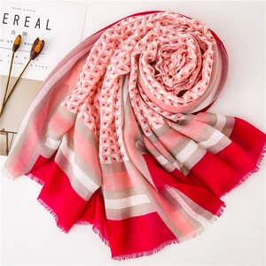 Detailansicht eines rosa Schals mit geometrischem Muster, zur Rosenform gefaltet mit Fransen