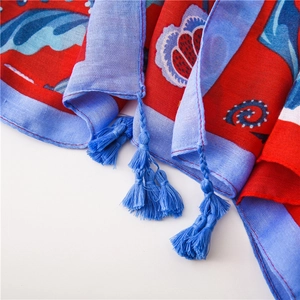 Detail of colorful exotic floral print on linen scarf with intricate blue fringe tassels