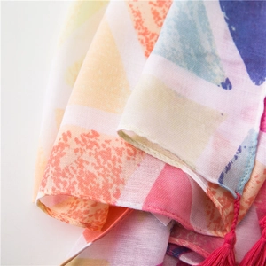 Detail eines farbenfrohen Schals mit Dreiecksmuster, rosa Quasten und weicher Textur