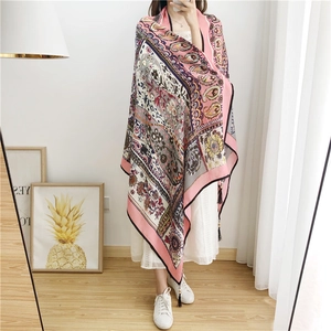 Close-up of pink paisley linen shawl featuring handmade wooden beads and black fringe trim