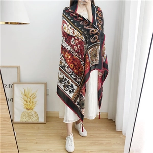 Detail of bohemian paisley shawl featuring red and black print with wooden bead fringe