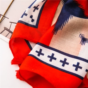 Close-up of red and navy geometric printed scarf with handcrafted tassels and linen texture