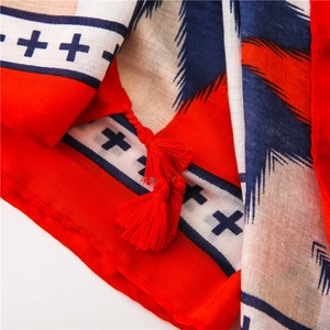 Detail view of red and blue geometric scarf with fringe tassels and palm leaf pattern