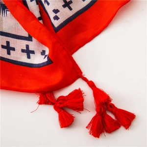 Close-up of geometric cross patterns and red tassel edges on a cotton linen shawl