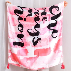Detailed texture of pink cotton linen scarf with black script lettering and red tassels