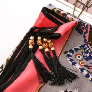 Close-up of bohemian scarf with paisley print, wooden beads, and decorative black tassels