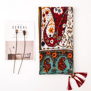 Macro detail of bohemian paisley scarf with handcrafted wooden beads and red tassels