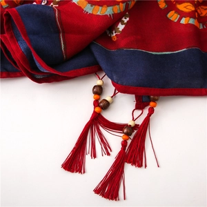 Detail of red and blue boho scarf featuring handmade wood beads and tassels on linen fabric