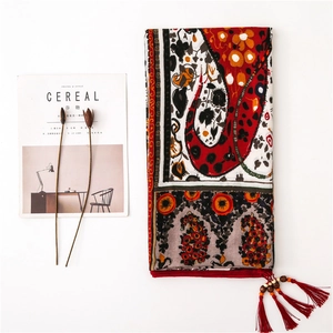 Detail of bohemian paisley shawl showing red fringe tassels and artisanal wooden beads
