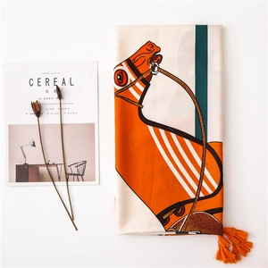 Detail view of cotton-linen scarf with horse print, twill pattern, and orange tassels