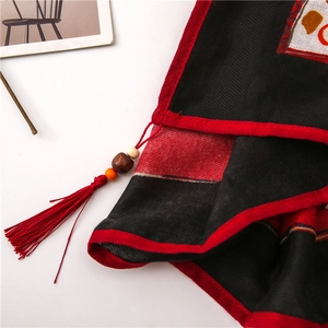 Detailed close-up of ethnic paisley scarf featuring handmade wooden beads and red tassels