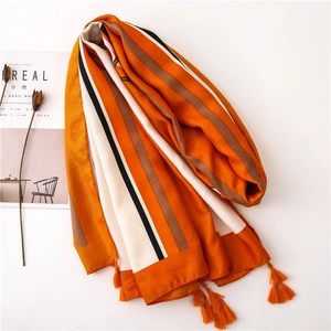 Detail of orange striped cotton linen scarf with soft fringe and premium fabric texture