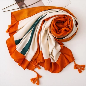 Close-up of linen-silk blend scarf with orange and white stripes and tassel charms