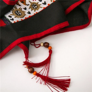 Close-up of cotton linen shawl featuring red tassels with wooden beads and paisley prints