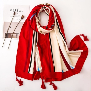 Detail of red striped cotton linen scarf featuring elegant corner tassel decorations