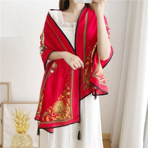 Detail of red Baroque shawl featuring golden floral patterns and elegant black fringe tassels