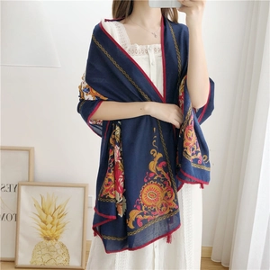 Detail of navy blue cotton linen scarf with vintage gold patterns and red tassels