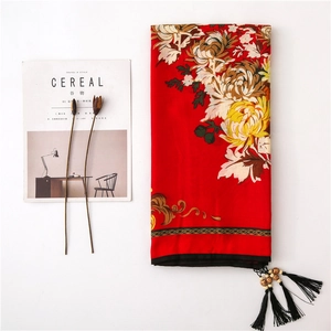 Detail of red floral scarf with yellow peony print, black tassels and wooden beads